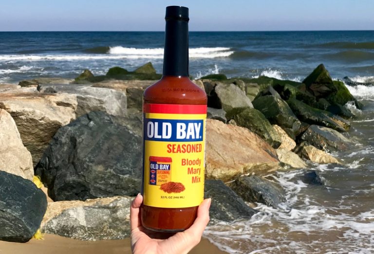 old bay bloody mary mix bottle with rocks and ocean in background