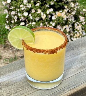 GEORGE’S® Chili Lime Mango Margarita served in chili/salt rimmed glass with lime garnish