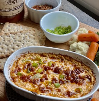 large bowl of GEORGE’S® Baked Cheese Dip served on cutting board with crackers and vegetables