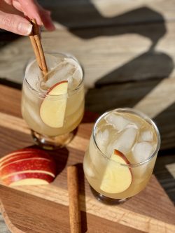 hand inserting cinnamon stick into a GEORGE’S® Fresh Apple Margarita