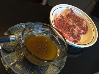 GEORGE’S® Bloody Mary Marinade in bowl with wisk next to 2 steaks on a plate