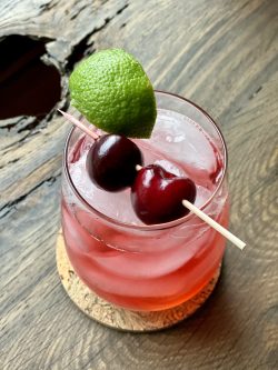GEORGE’S® Cherry Sour served with cherries and lime slices garnish