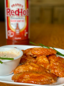 bloody Mary buffalo chicken wings and dressing on plate with bottle of FRANK'S RedHot® sauce