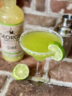 GEORGE’S® Melon Margarita served in salt rimmed glass and lime wedge garnish