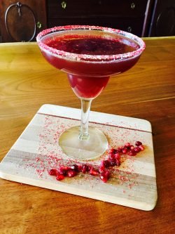 GEORGE’S® Pomegranate Margarita served in glass rimmed with pomegranate seeds and sugar