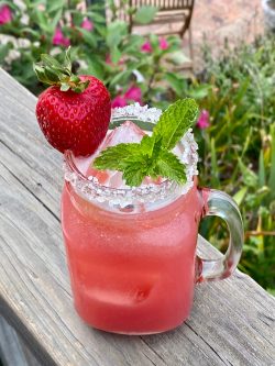 GEORGE’S® Strawberry Mint Margarita served in salt rimmed glass with strawberry and mint for garnish