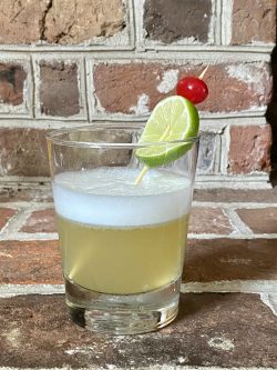 GEORGE’S® Tequila Sour served in glass with cocktail cherry and lime wedge garnish