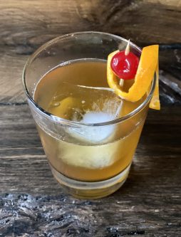 GEORGE’S® Whiskey Sour served in small glass with orange peel and cocktail cherry garnish