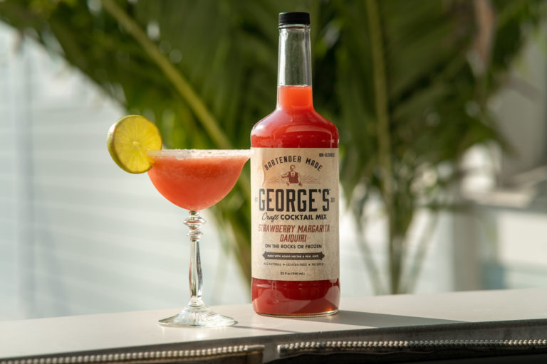 Strawberry Margarita Daiquiri in glass next to GEORGE’S® Craft Cocktail Mix bottle
