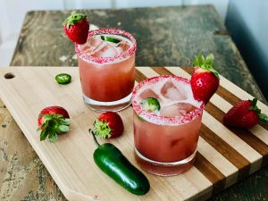 cocktails on cutting board with strawberries and jalapenos