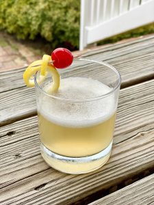 cocktail with cherry and lemon rind on deck